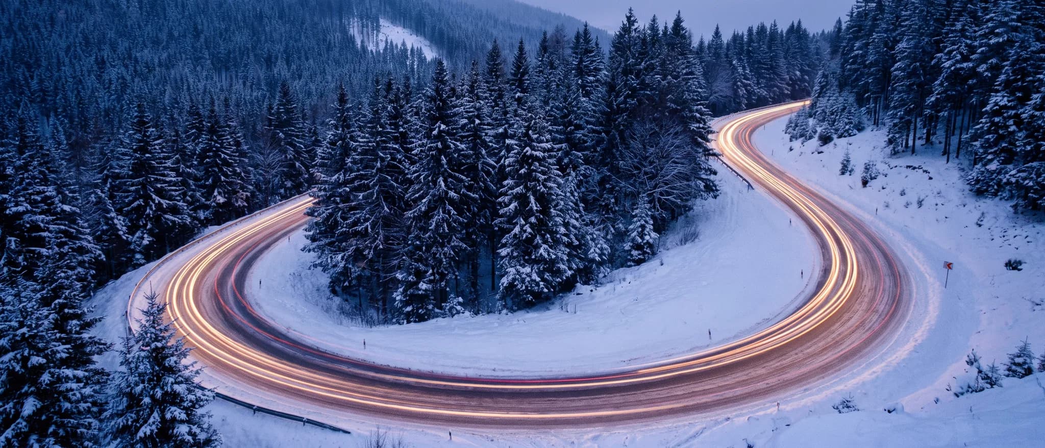 Alacakaranlıkta karlı virajlı dağ yolu